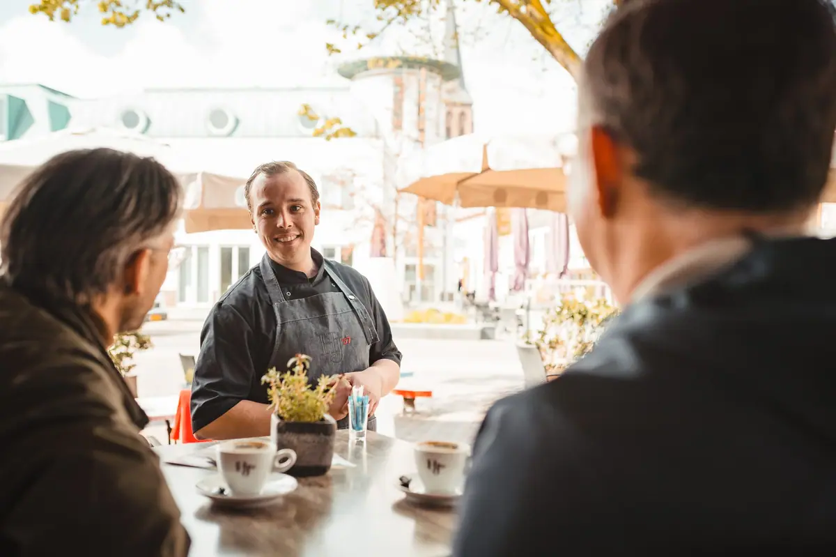 Een collega van HJ'57 serveert koffie op het terras